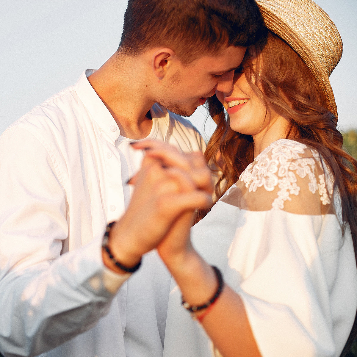 A young couple in white clothing sharing a warm embrace, radiating love and affection towards each other.