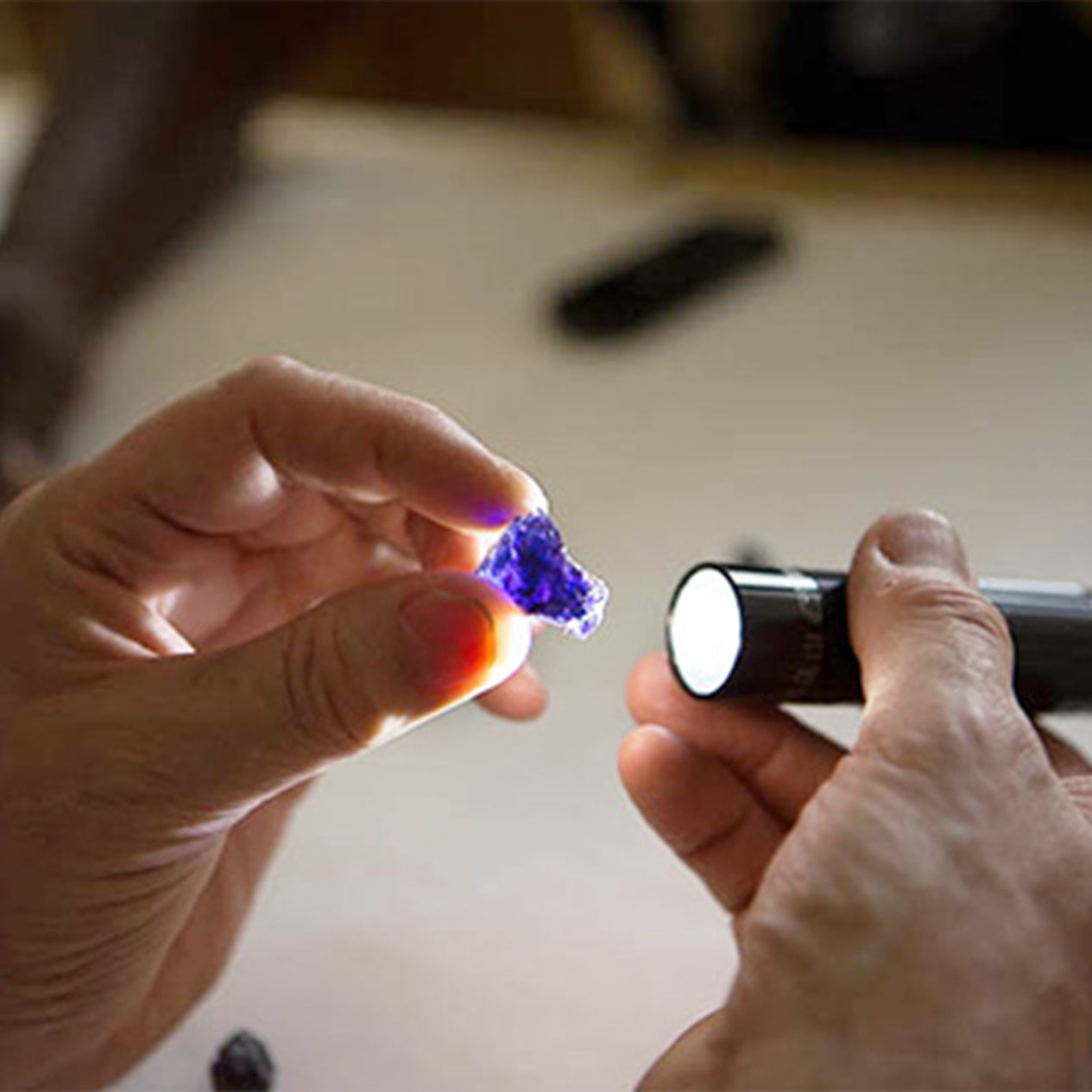 Shimansky Jeweller pointing a torch at a Tanzanite gem to show the colour