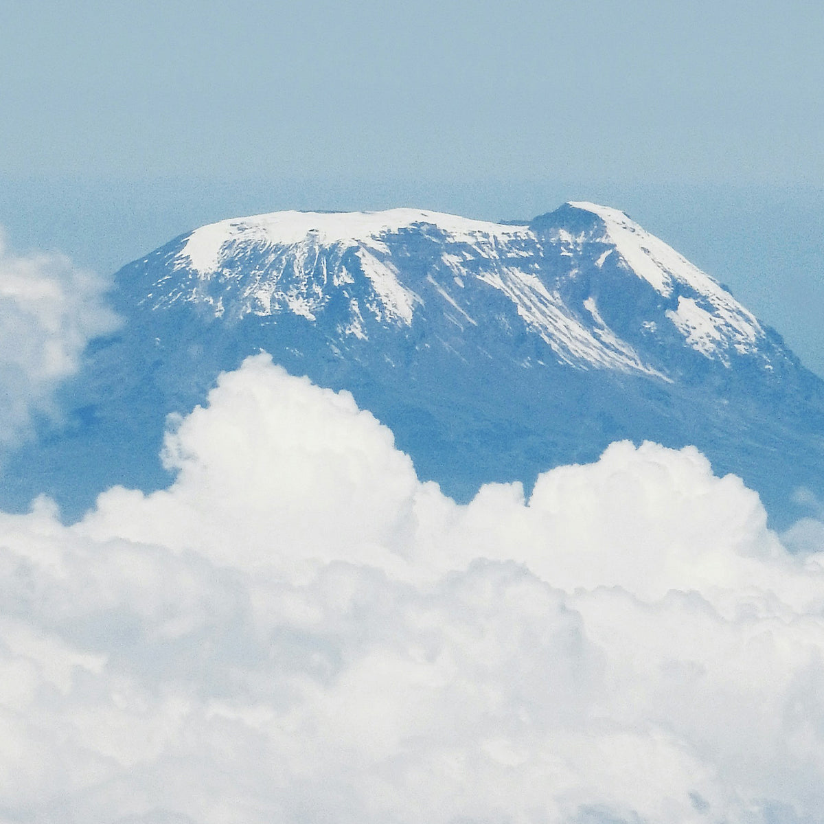 Mount Kilimanjaro with snow on top and surrounded by clouds